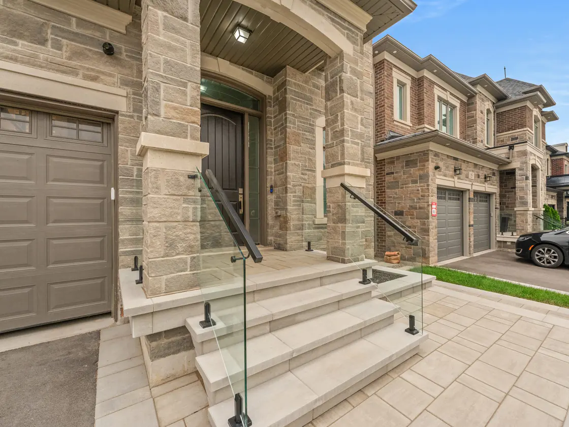Frameless glass guard with a black handrail on front steps