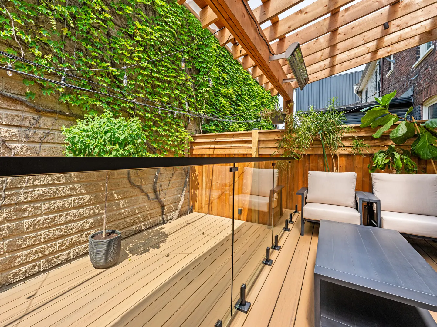 Frameless glass guard along a composite deck under a pergola