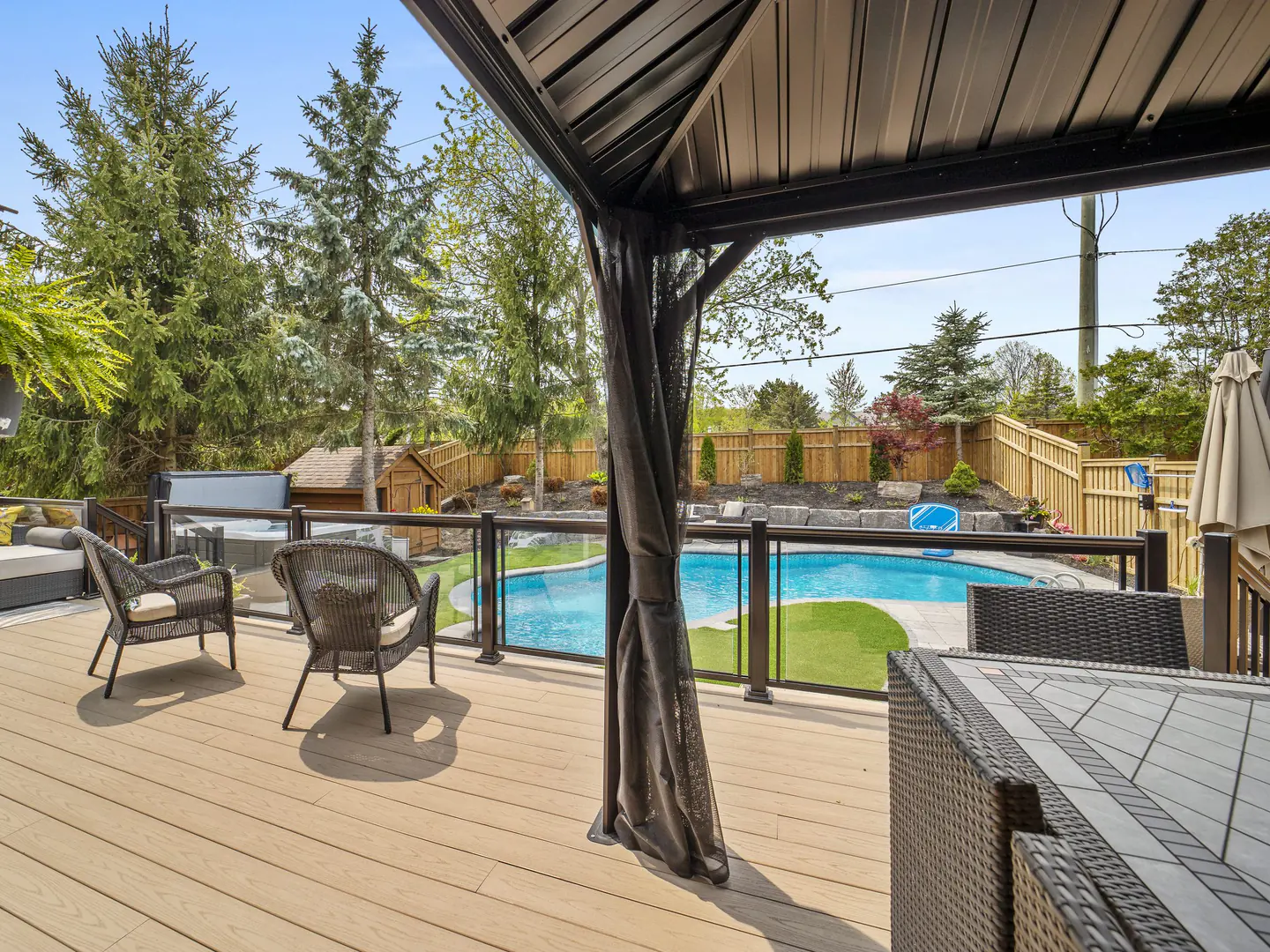 Glass railing with black posts beside a backyard pool