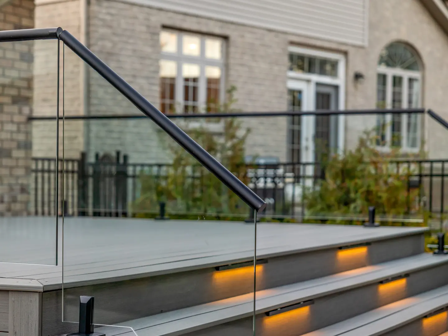Glass stair guard with a black handrail and step lighting